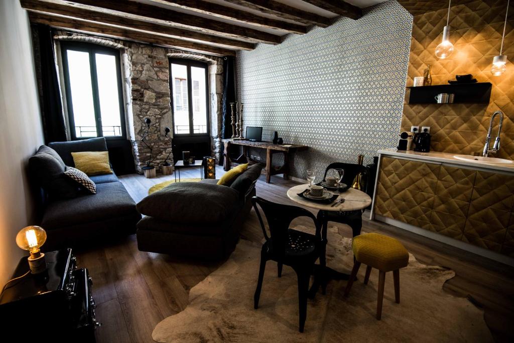 a living room with a couch and a table and chairs at "Un Lieu Unique" le Gold et le Cocon in Annecy