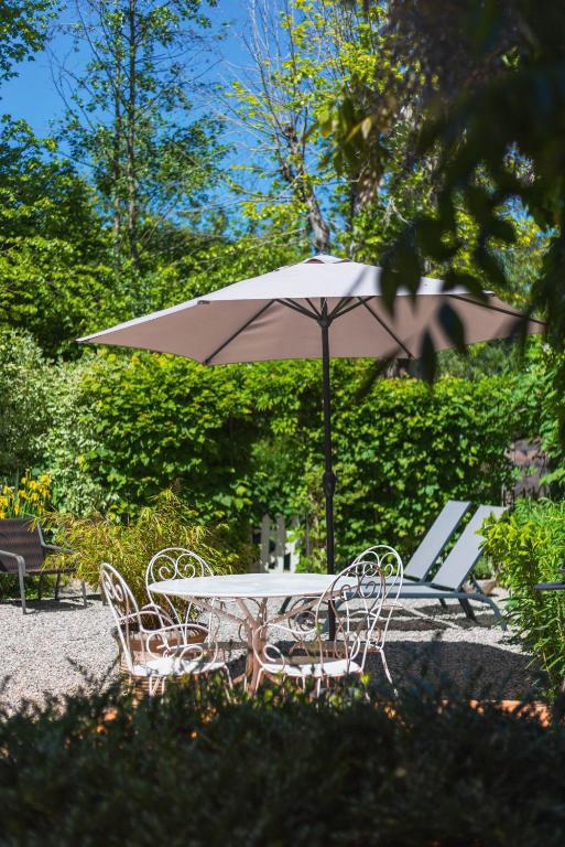 une table et des chaises avec un parasol et un banc dans l'établissement Gîte du Rouard, à Camiers