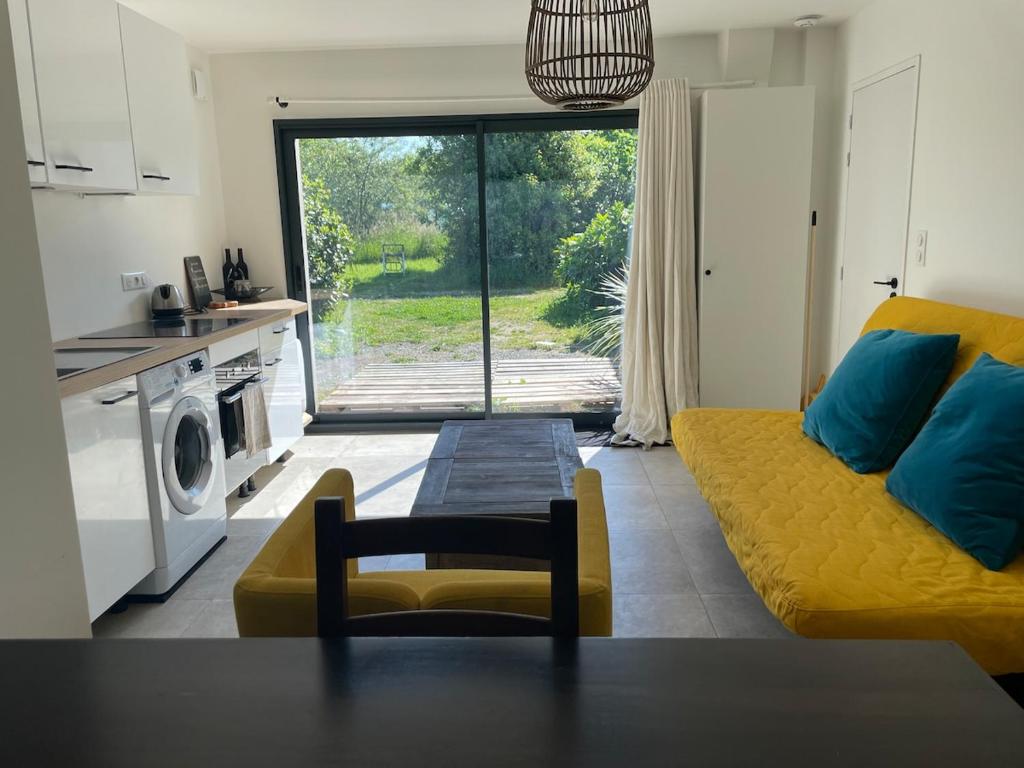 un salon avec un canapé jaune et une table dans l'établissement Petit gîte cosy proche de la mer, jardin privatif, à Clohars-Fouesnant