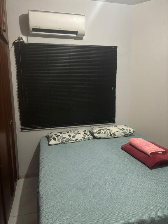 a bedroom with a bed with a pillow and a window at Quarto Centro de Palmas ao lado da JK in Palmas