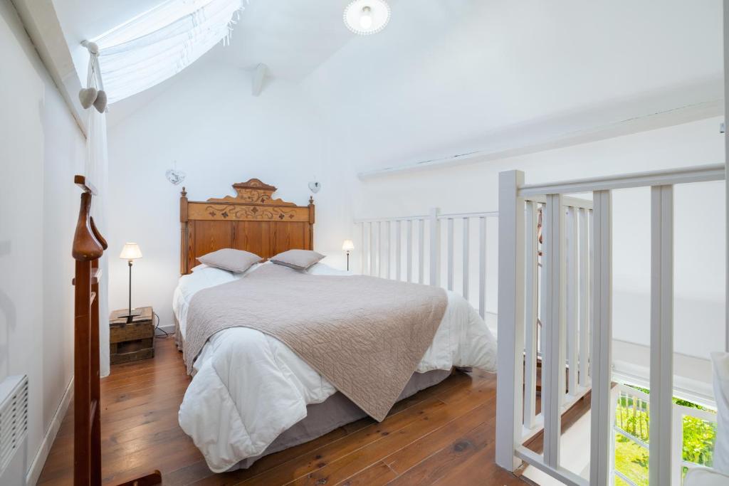a white bedroom with a large bed with a wooden headboard at Gîte du Rouard in Camiers