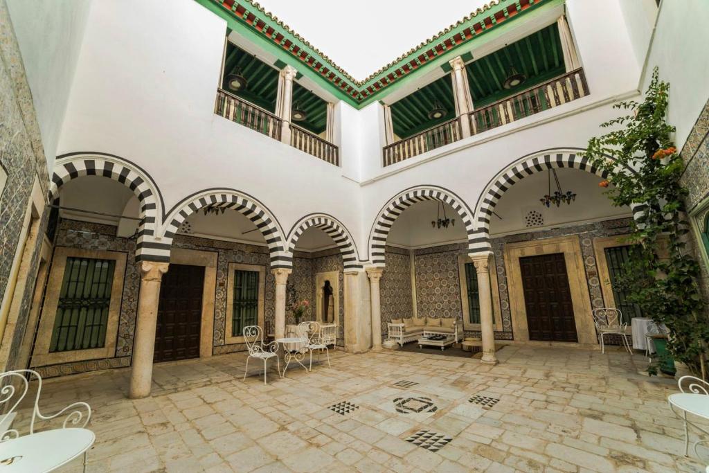 Dar Ben Gacem في تونس: غرفة كبيرة بها مقوسات وطاولات وكراسي