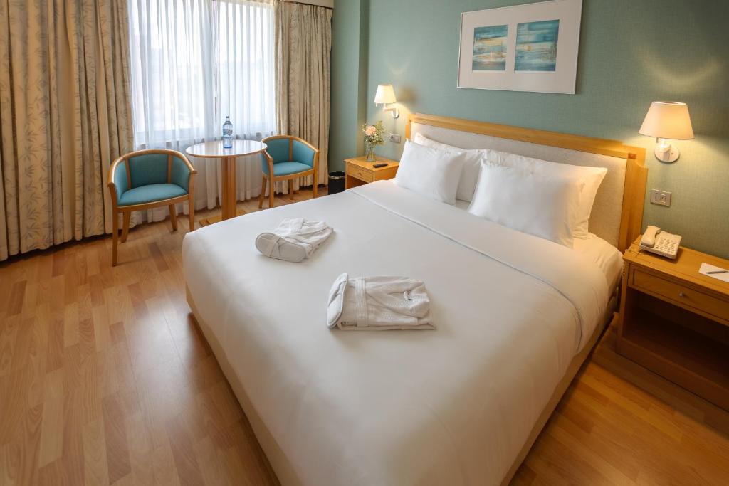 A double room has a large bed, a curtained window and a compact sitting corner.