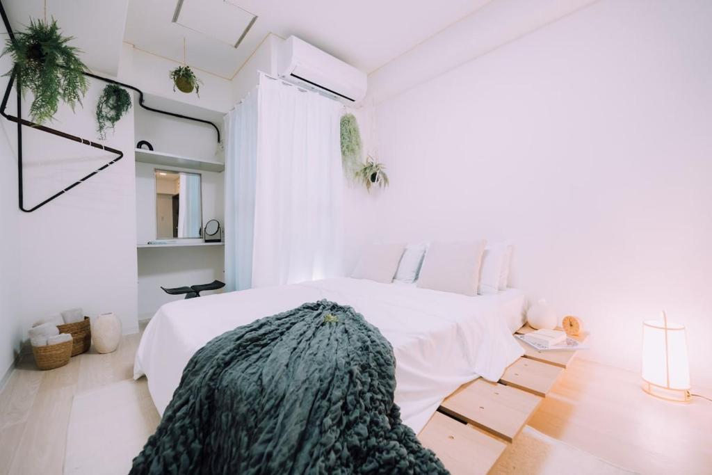 Un dormitorio con una cama blanca con una manta verde. en Minimalist Loft 8 Namba Compact Studio and Gym MA801, en Osaka