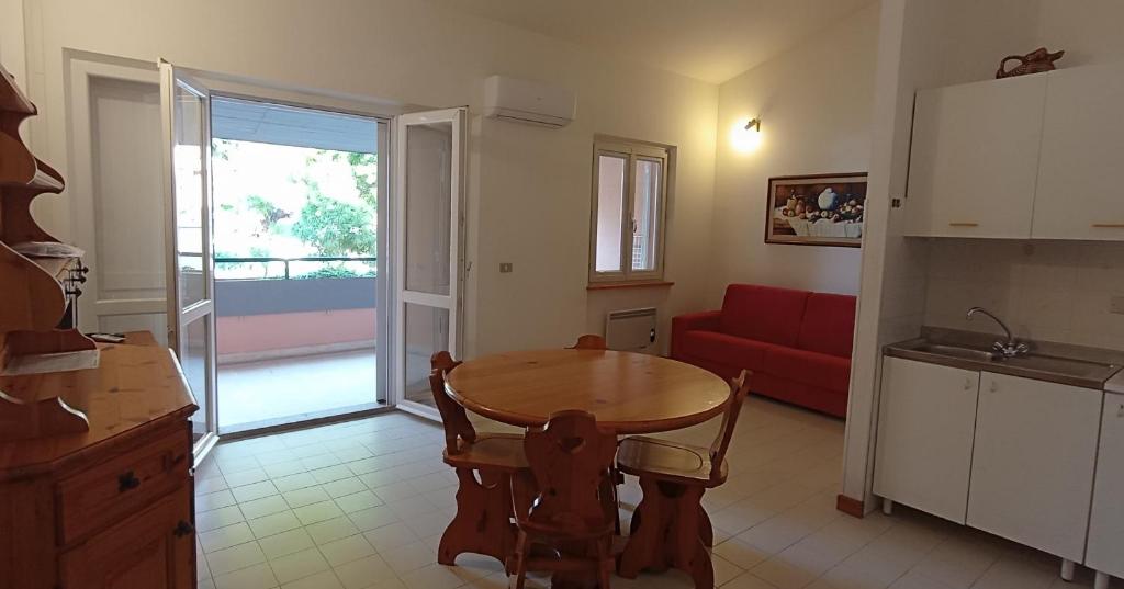 eine Küche und ein Wohnzimmer mit einem Tisch und einem roten Sofa in der Unterkunft Casa Bugarini in Marcelli
