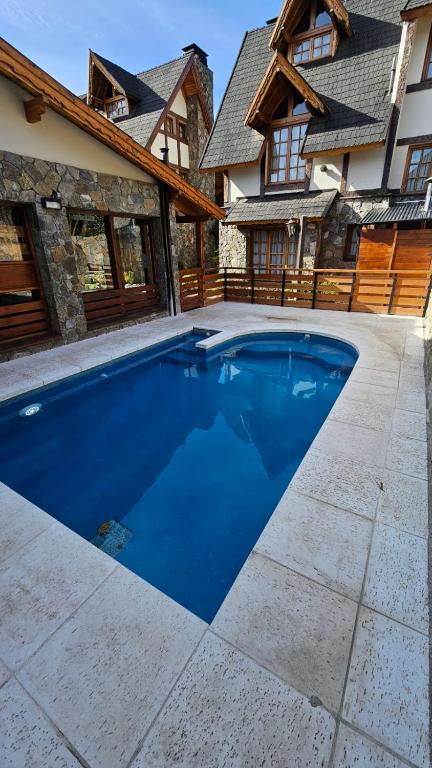 a large blue swimming pool in front of a house at Cabañas Woodland in San Martín de los Andes