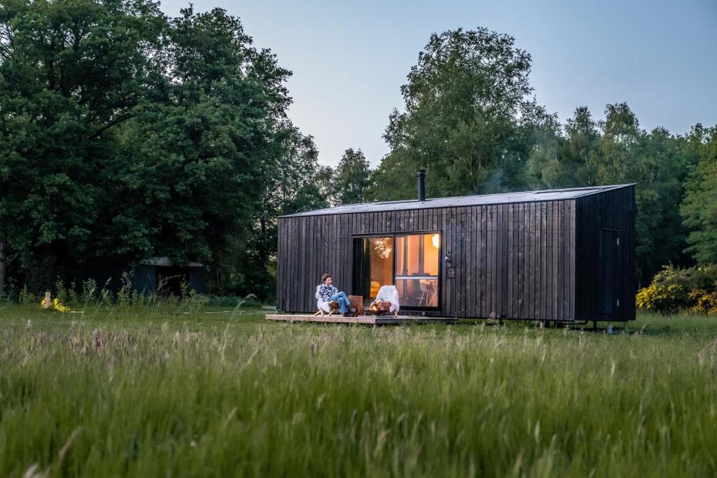 a couple sitting in a tiny house in a field at Ecopark Twente Cabin Tilligte in Tilligte
