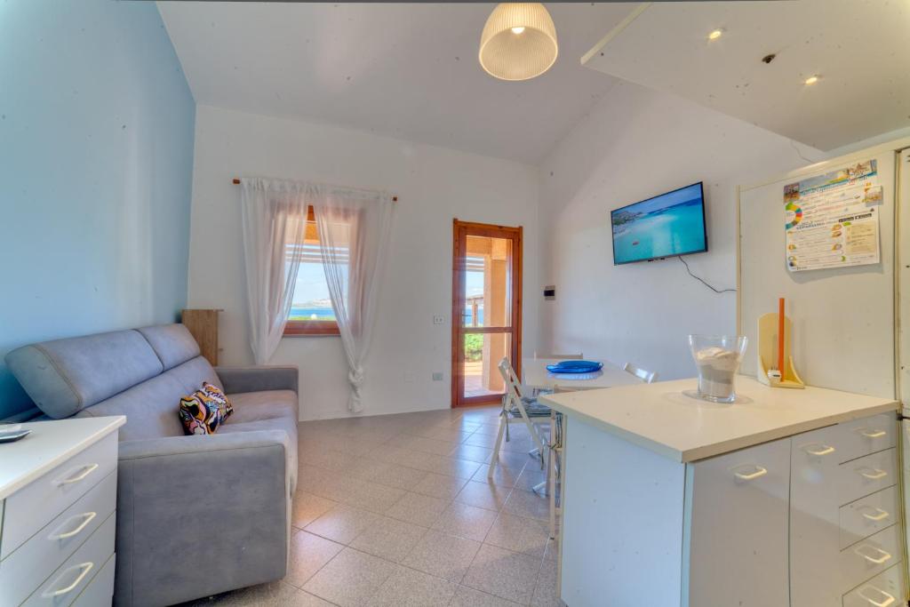 a kitchen and living room with a couch and a table at SulMare Apartment in Stintino