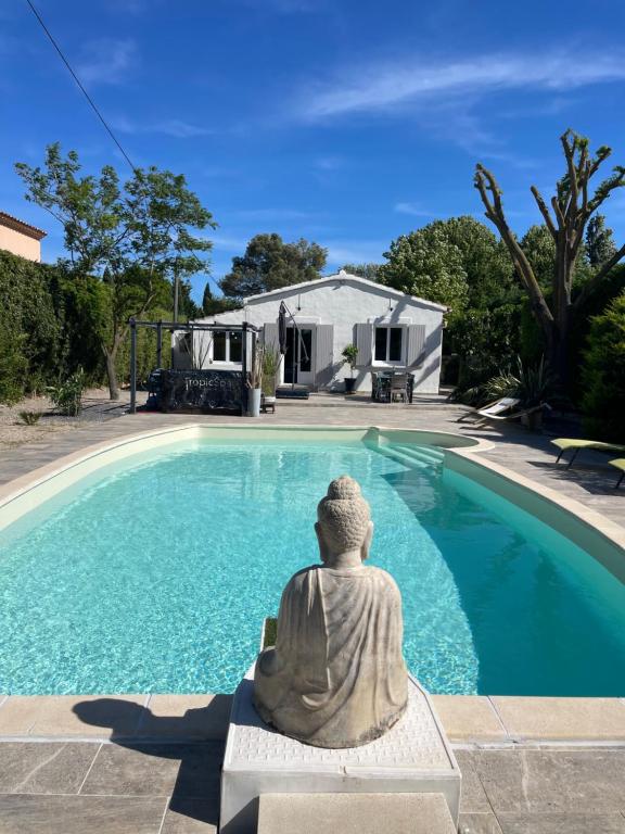a statue sitting on a bench next to a swimming pool at Entre ciel et terre in Le Thor