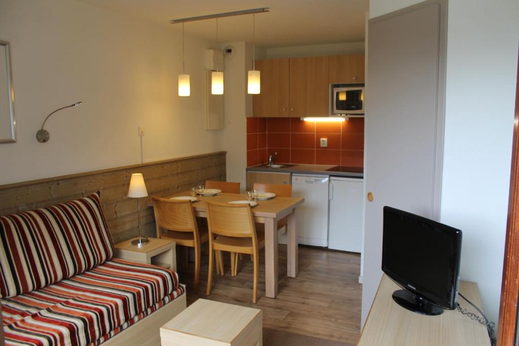 a living room and kitchen with a couch and a table at Résidence Britania Clés Blanches in La Tania