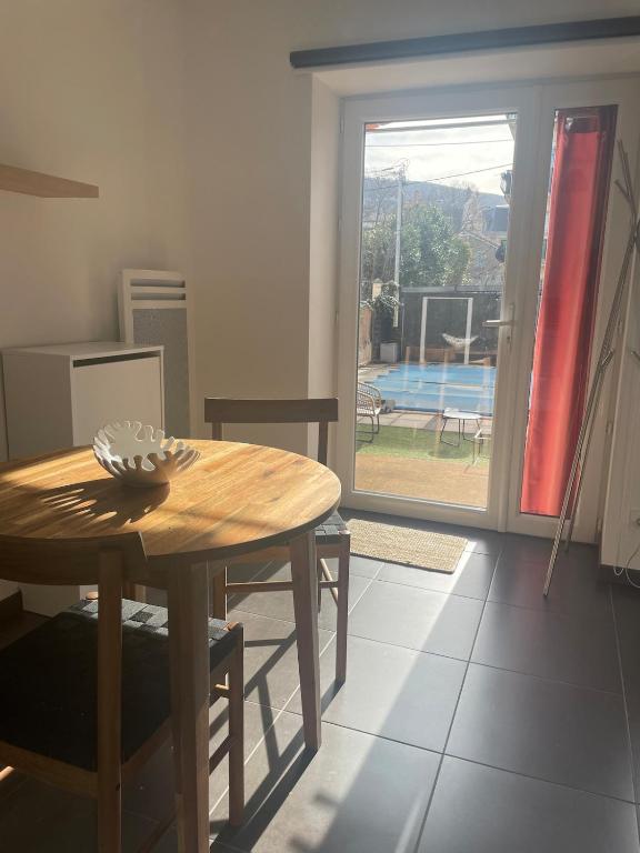 a dining room with a table and a view of a pool at Chez Ambre et Lulu - Appartement centre ville avec piscine in Millau