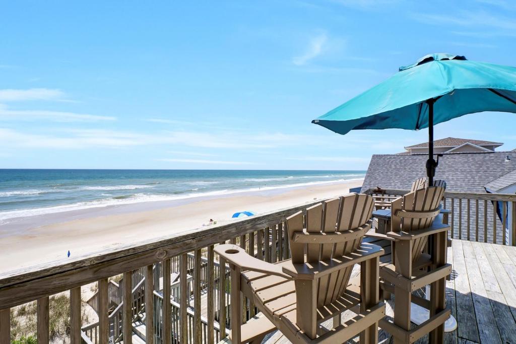 a deck with two chairs and an umbrella on the beach at 3950 Island Drive in North Topsail Beach