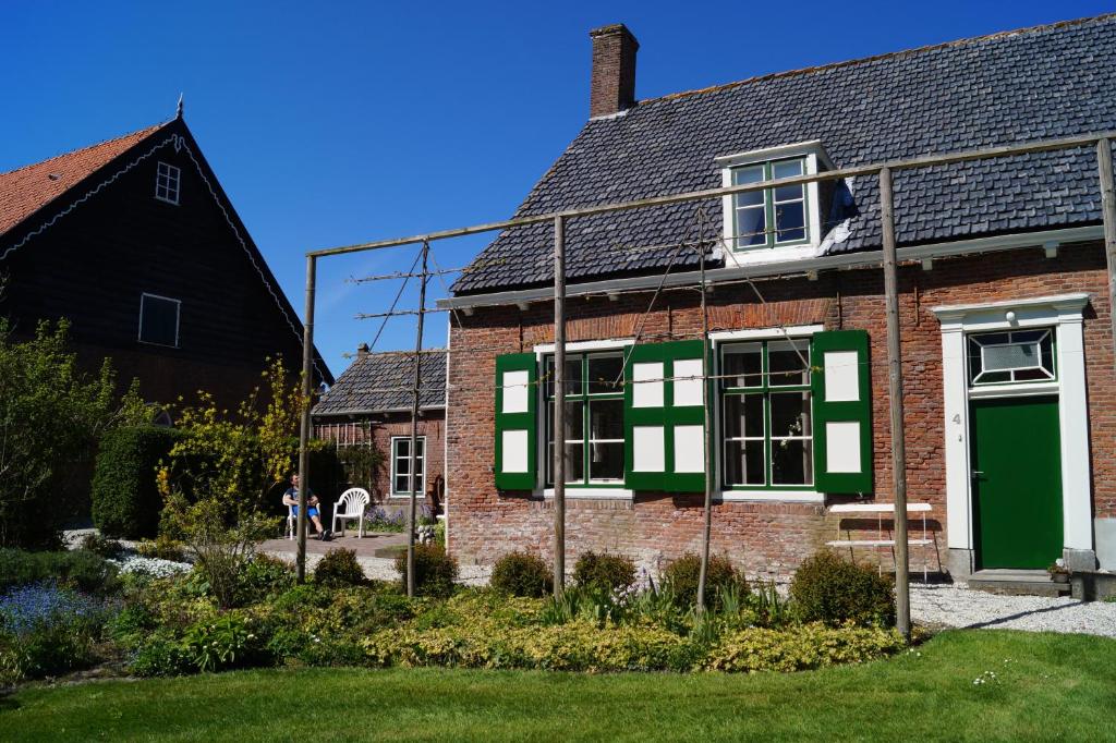 a brick house with green and white shutters at Vakantiehuis 't Boerenhuis in Aagtekerke