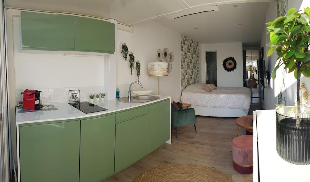 une cuisine avec des armoires vertes et une chambre avec un lit dans l'établissement Studio port nature 2, au Cap d'Agde