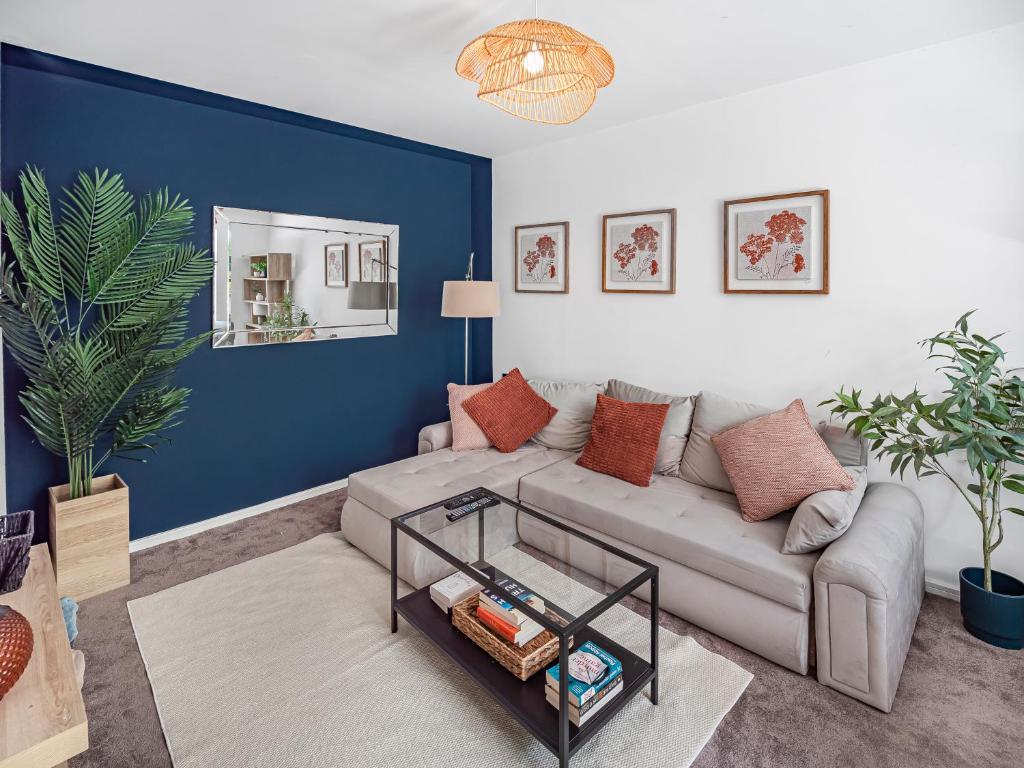 a living room with a couch and a blue wall at Chic Riverside Retreat Salford 4bd free parking in Manchester