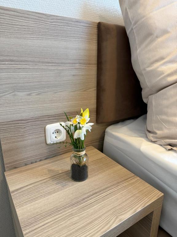 a vase of flowers on a table next to a bed at Aparthotel Emilia in Bargteheide