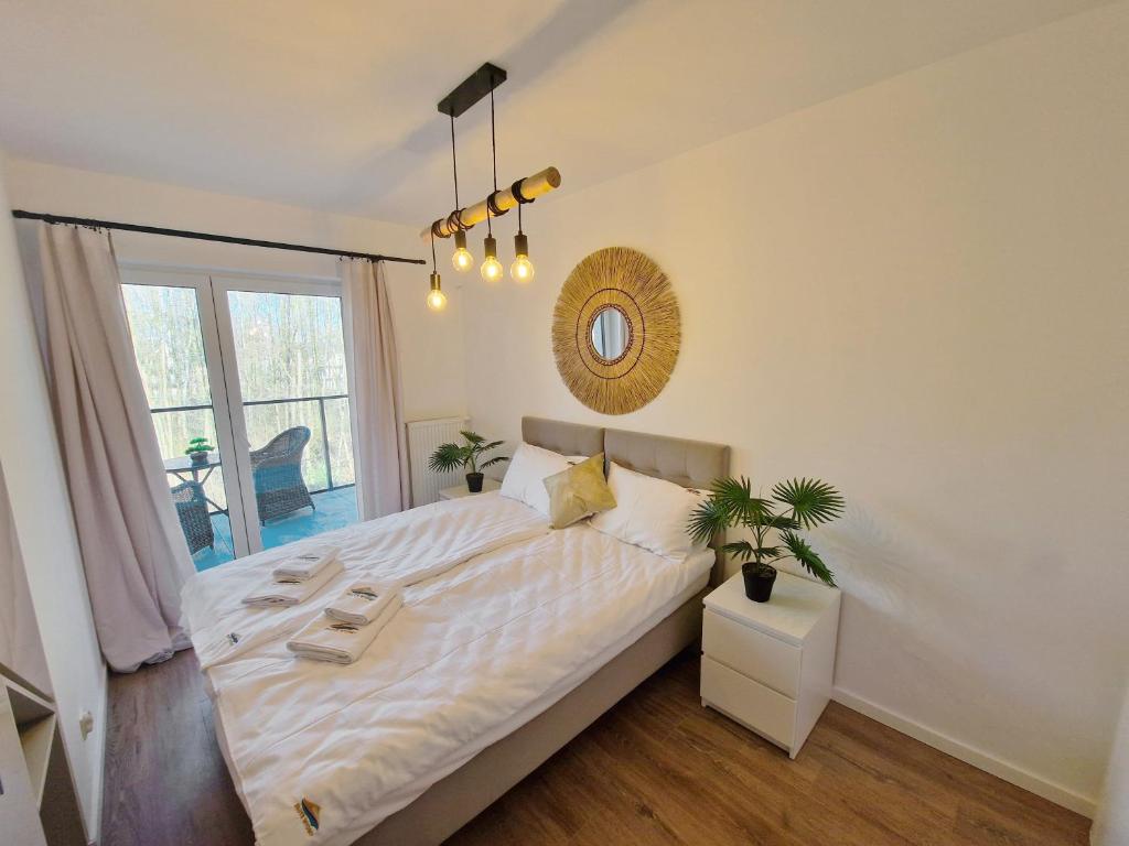 Schlafzimmer mit einem großen weißen Bett und einem Spiegel in der Unterkunft Apartamenty Złote Wydmy - Plażowa Park Międzywodzie in Międzywodzie
