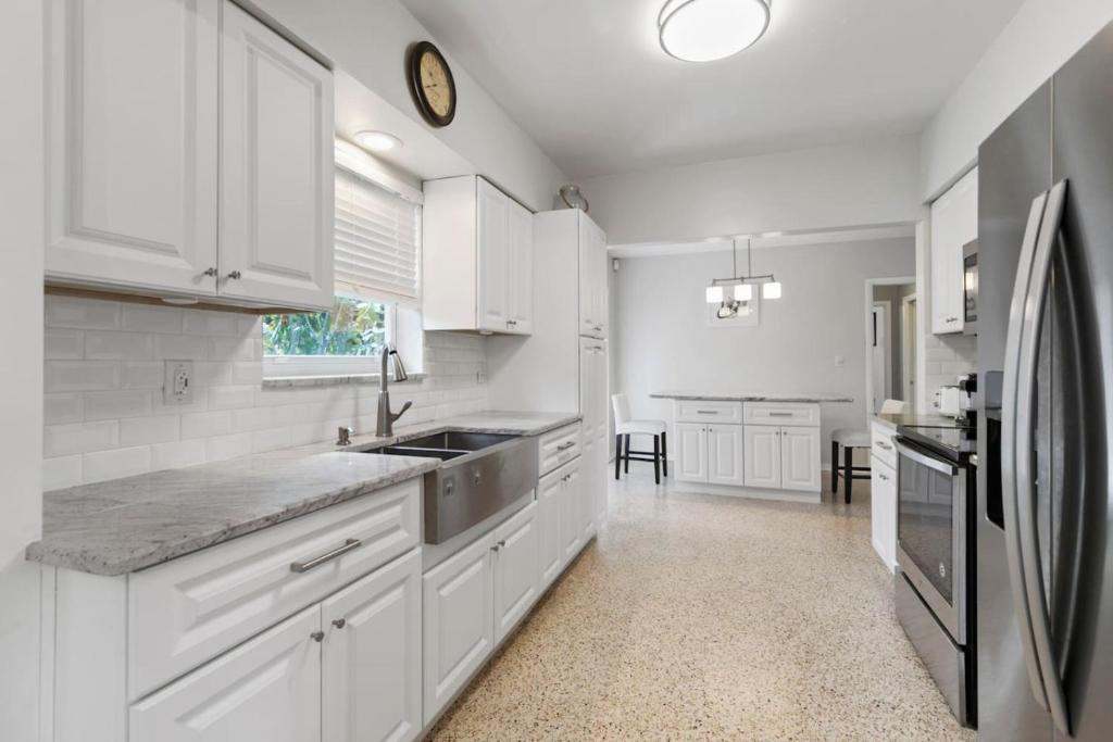 a kitchen with white cabinets and a stainless steel refrigerator at 2 Bedroom Cozy House Near Barry University in Miami