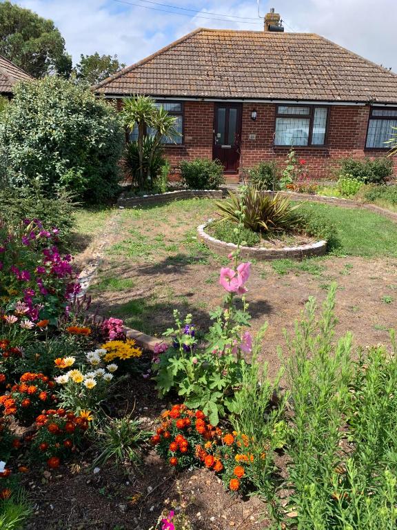 a garden with flowers in front of a house at Sea Shells in Greatstone