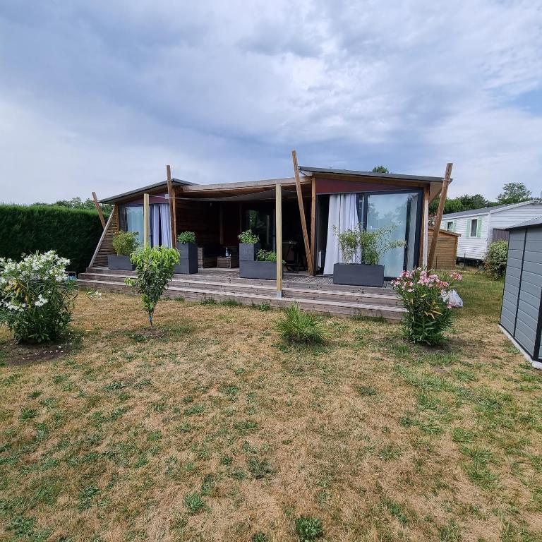 une maison avec une terrasse couverte ornée de plantes dans une cour dans l'établissement Magnifique Chalet, à La Teste-de-Buch