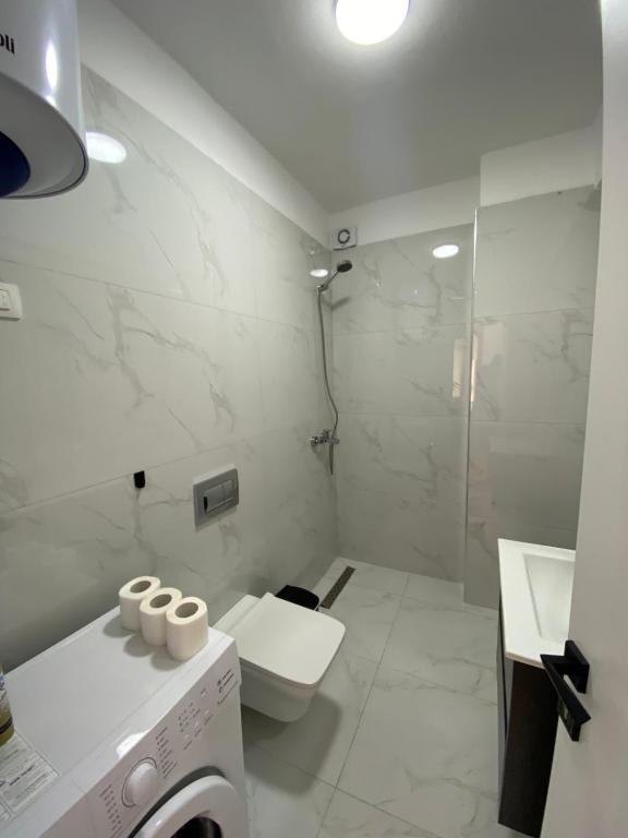 a white bathroom with a toilet and a washing machine at Hira apartment in Golem
