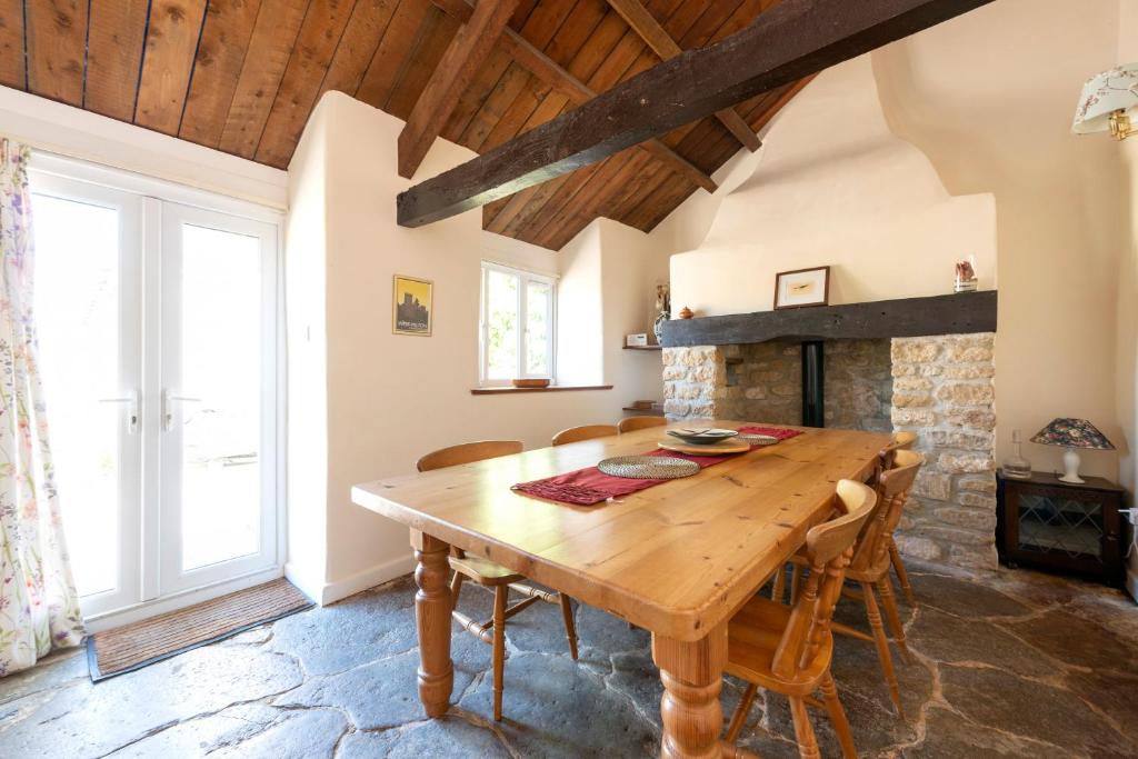a dining room with a wooden table and a fireplace at Tanglewood Cottage - Lancombes House in Powerstock