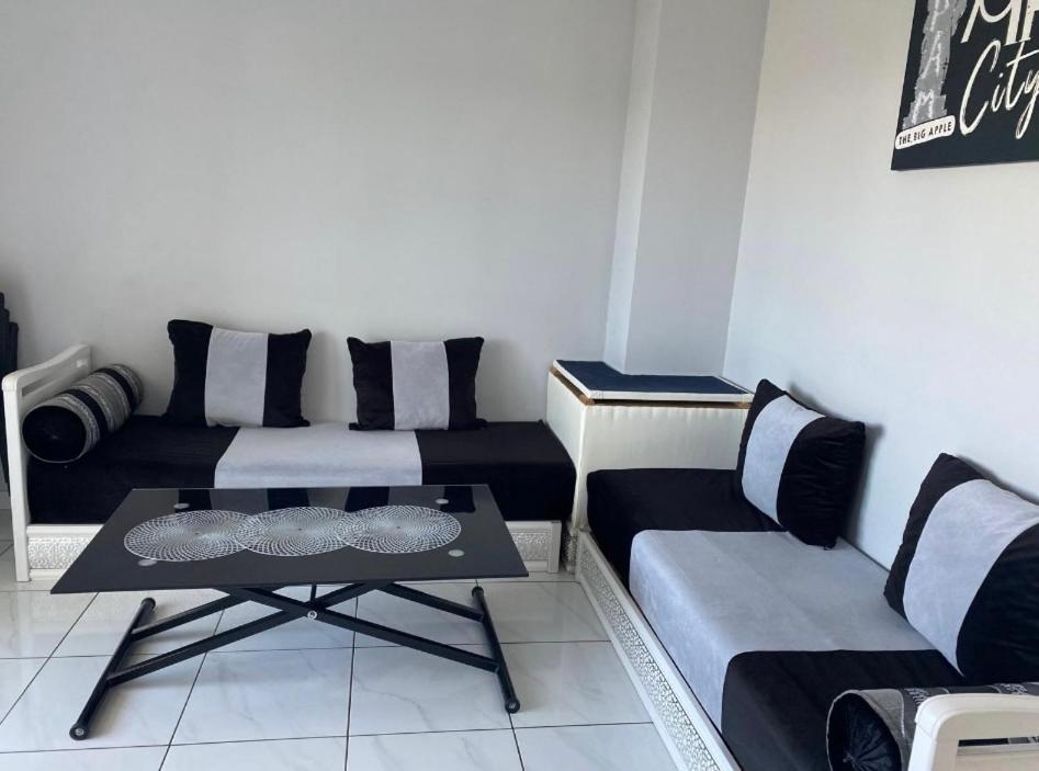 Cette chambre comprend deux lits, une table et un canapé. dans l'établissement Joli appartement limite Lyon 8, tram T4, à Vénissieux