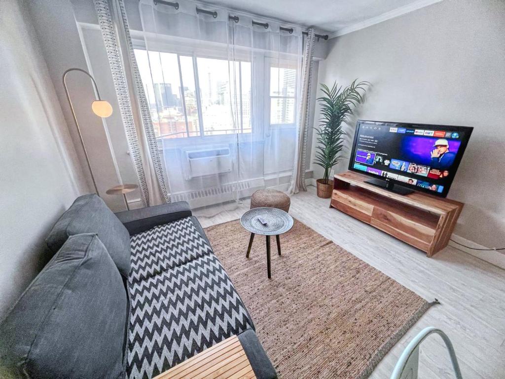a living room with a couch and a flat screen tv at Downtown Central Residences in Montréal