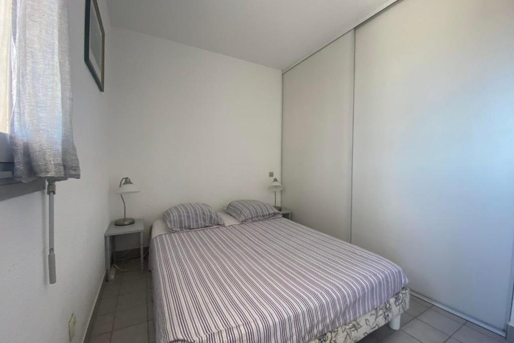 ein kleines Schlafzimmer mit einem Bett mit gestreifter Decke in der Unterkunft Sea & Relaxation Stay in Frontignan