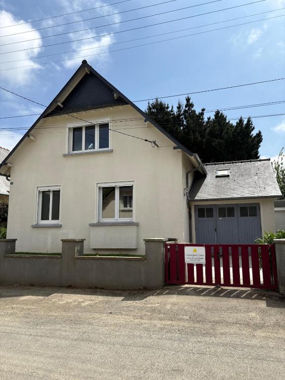 une maison blanche avec une clôture rouge devant elle dans l'établissement La maison des castors, à Paimpol