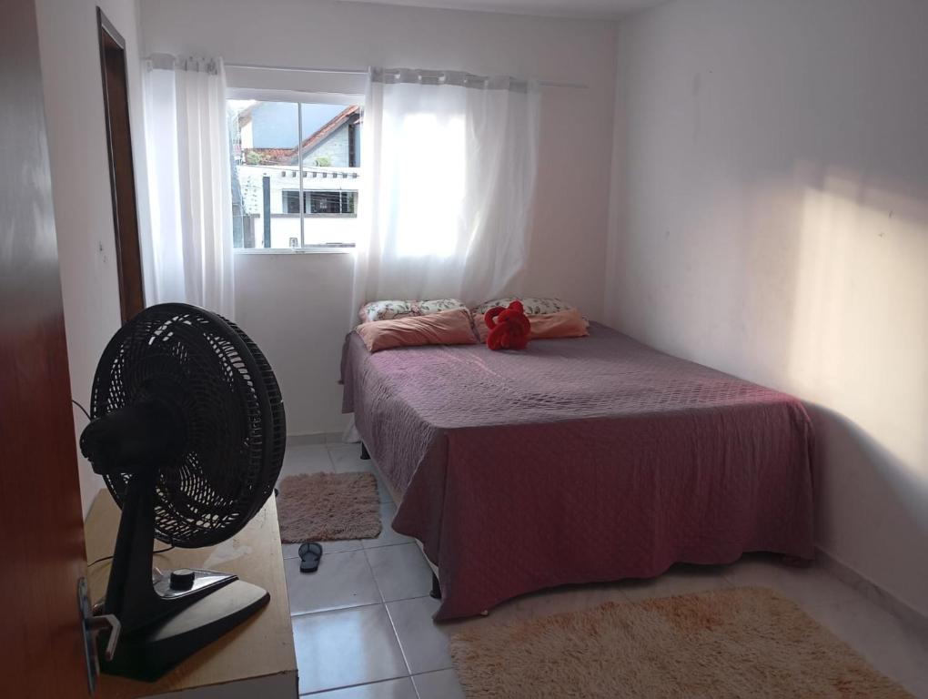 a bedroom with a bed with a fan and a window at Casa para temporada no São João in Campina Grande