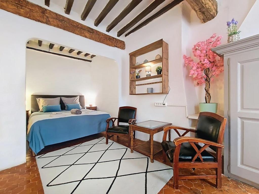 a bedroom with a bed and two chairs and a table at Appartement spacieux en plein cœur du village in Cotignac