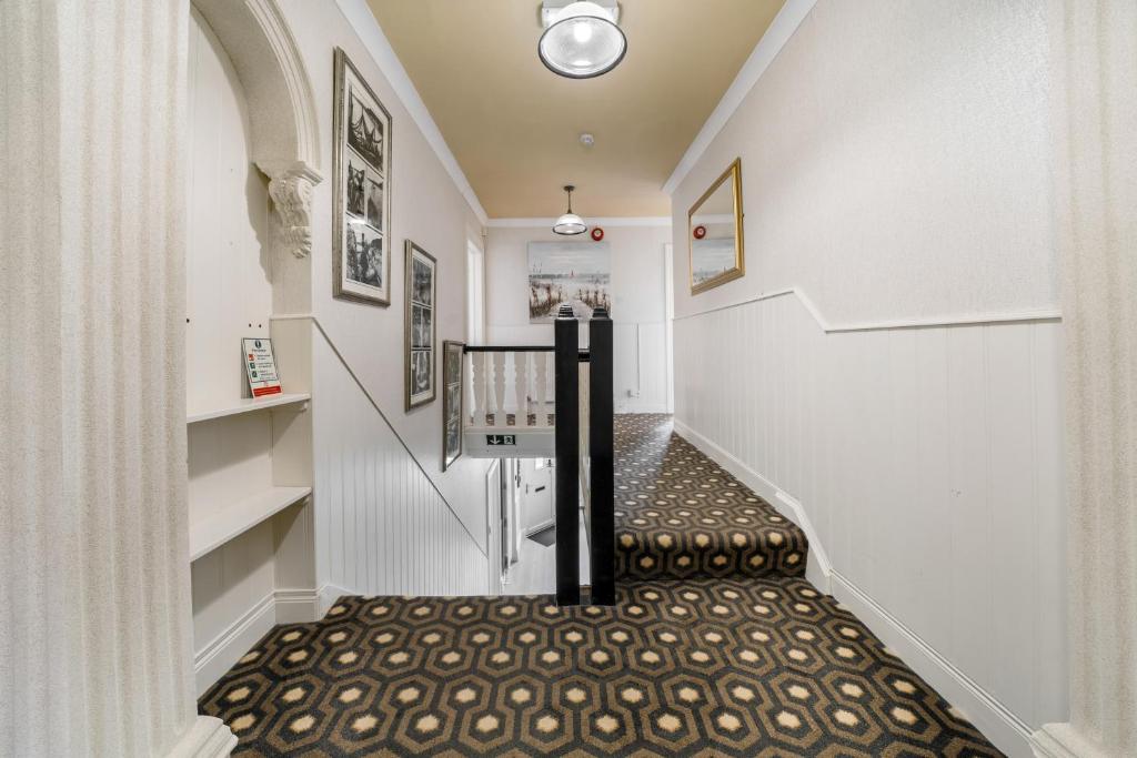 a hallway with white walls and a stairway with a black railing at Anvershiel House in Portrush