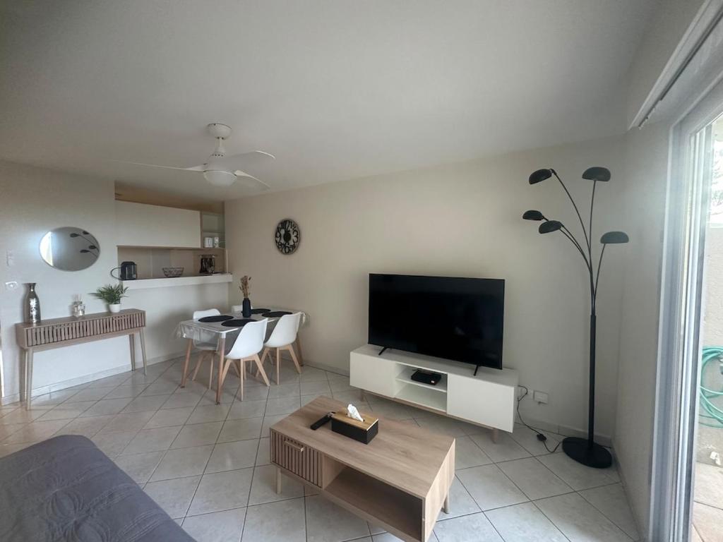 un salon avec une télévision et une table dans l'établissement Front mer magnifique appartement en rez-de-jardin, à Canet