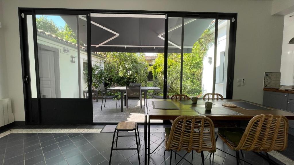 une cuisine avec une table et des chaises ainsi qu'une grande fenêtre dans l'établissement MAISON - Authentique échoppe Bordelaise avec jardin, à Bordeaux