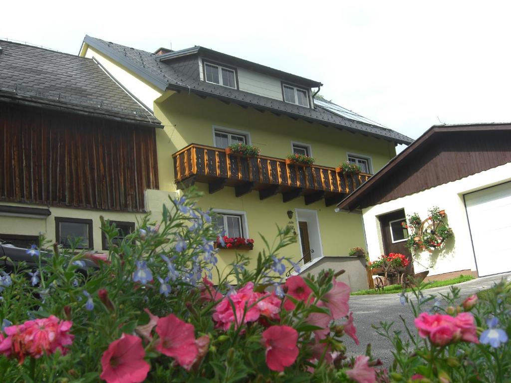 ein gelbes Haus mit einem Balkon mit Blumen in der Unterkunft Haus Adler in Gröbming