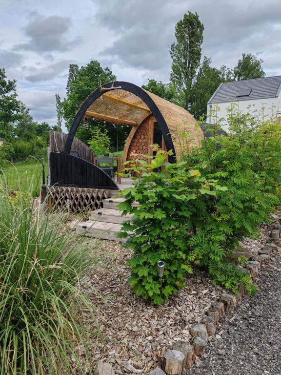 un jardin avec une arche en bois et quelques plantes dans l'établissement La cabane de l'étang, à Kerprich-aux-Bois
