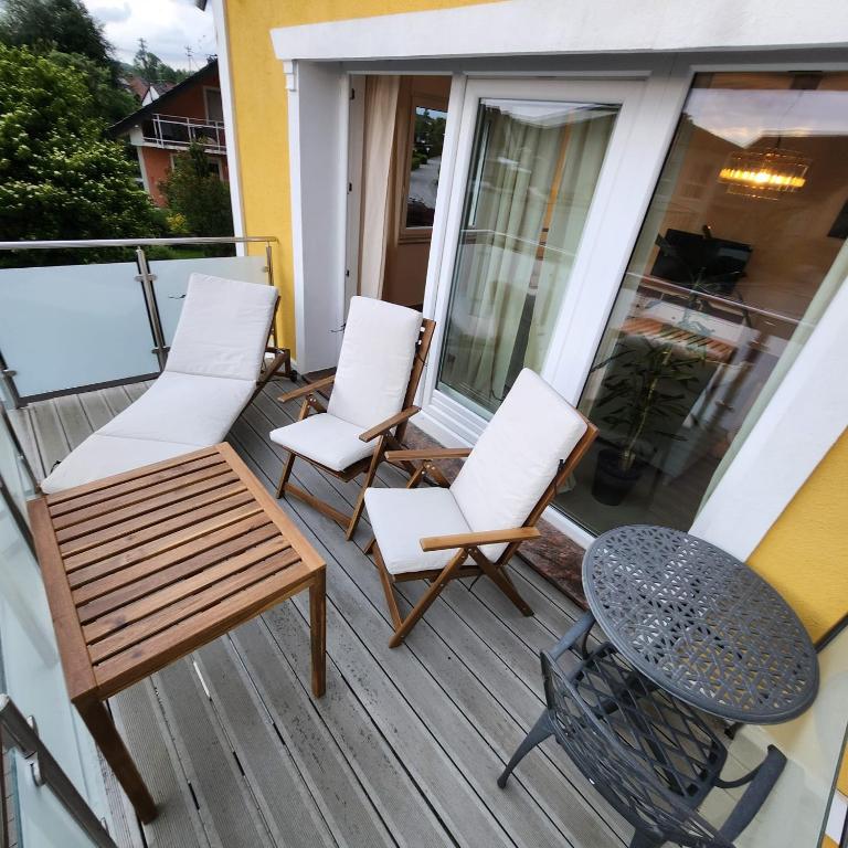 a porch with white chairs and a table and a table at Esmeralda Ferienwohnung mit Sonnenterrasse & großem Parkplatz in Ebersbach-Musbach
