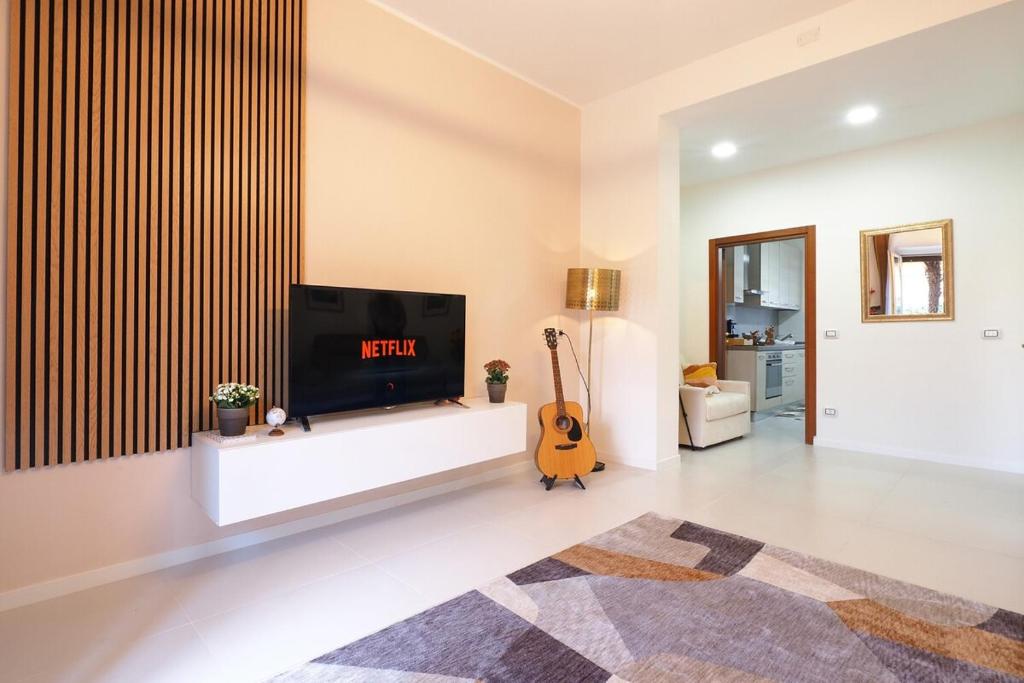 un soggiorno con TV a schermo piatto e chitarra di Melody's Garden House a Como
