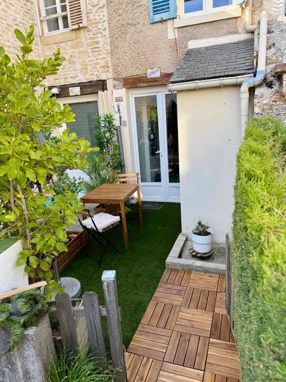 un petit jardin avec une table et une terrasse en bois dans l'établissement La Victoire, à Saint-Aubin-sur-Mer