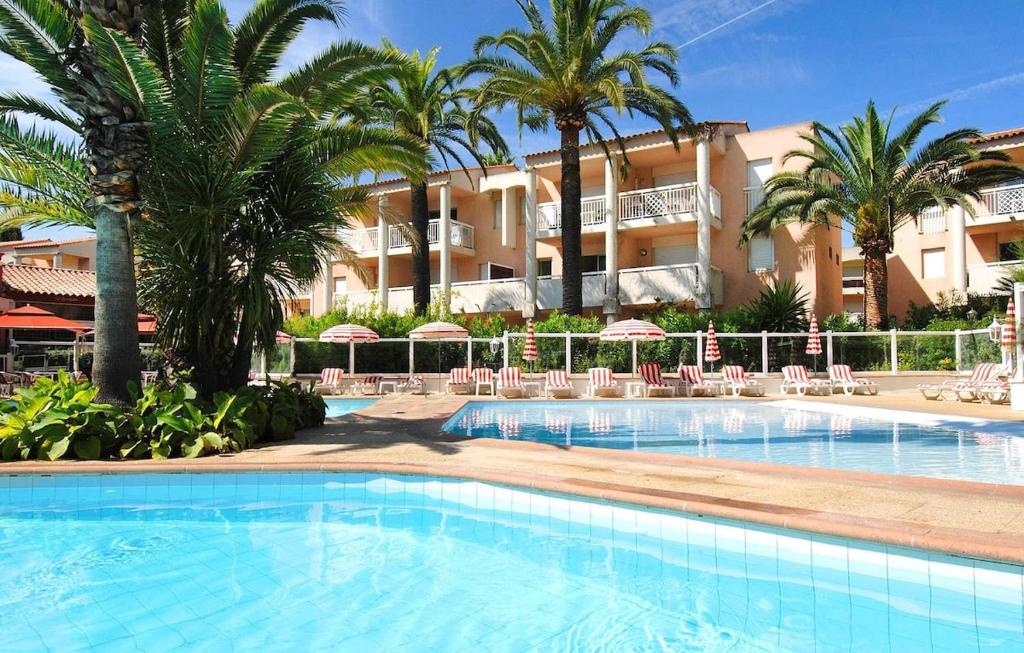 une piscine avec des palmiers en face d'un hôtel dans l'établissement Appartement 2 chambres à 5 min à pieds de la plage et tout commerce, à Vallauris