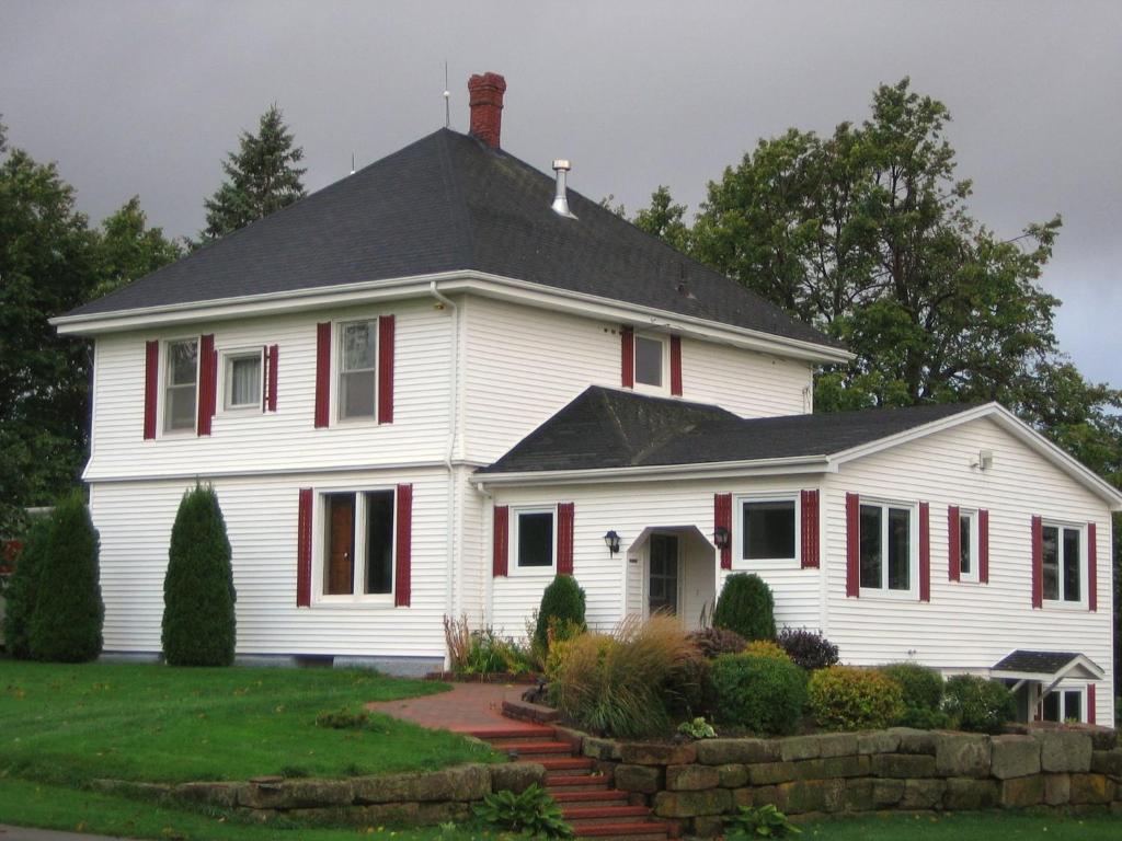 une maison blanche avec un toit noir dans l'établissement Linden Homestead, à Stanley Bridge