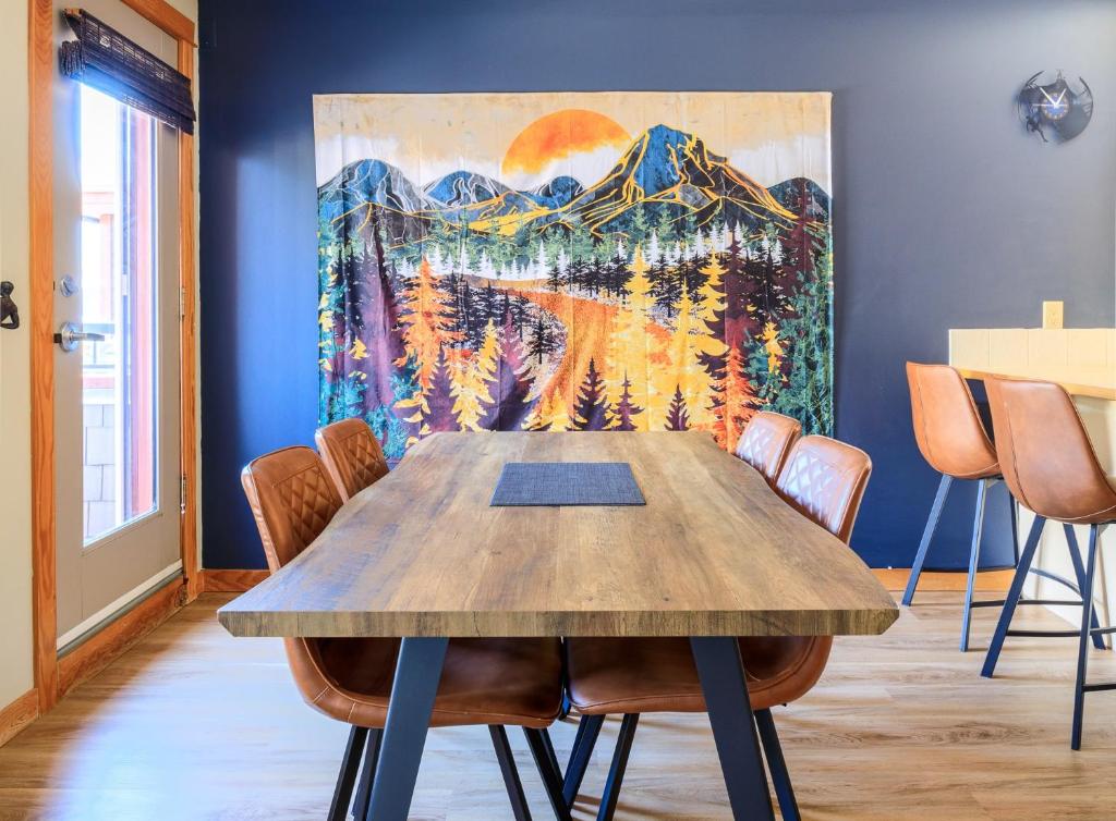 a table in a room with a painting on the wall at Boardwalk Bliss - Top Floor Downtown Condo in Canmore