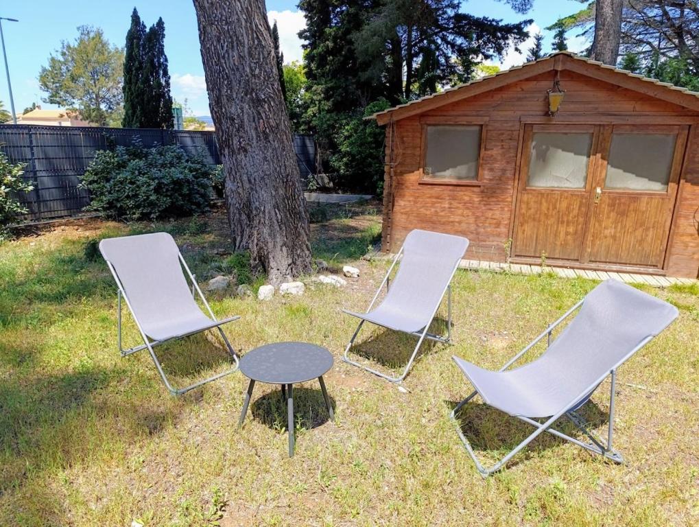 un groupe de trois chaises et une table et une cabine dans l'établissement Maison climatisée avec Grand Jardin - 10 min à pied du Brusc et de sa plage, à Six-Fours-les-Plages