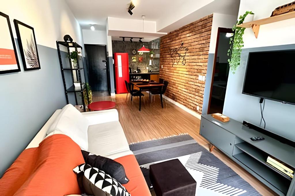 a living room with an orange couch and a flat screen tv at F202 Praia Cond Tranquilo Vaga Ar Elevador in Vitória