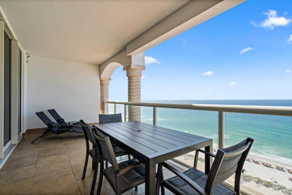 Una mesa y sillas en un balcón con vista al mar. en Beach Club Resort & Spa Unit 1502, en Pensacola Beach