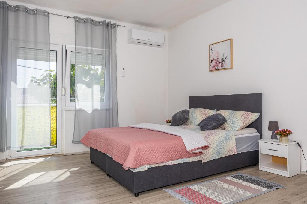 a white bedroom with a bed and a window at Dvokrevetna soba Lela in Crikvenica
