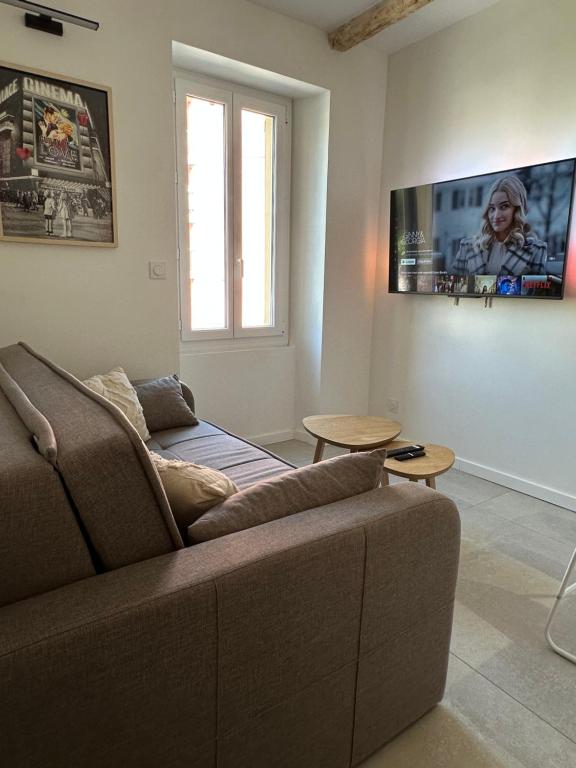 un salon avec un canapé et une télévision au mur dans l'établissement Appartement T2 rénové climatisé, à Mandelieu-la-Napoule