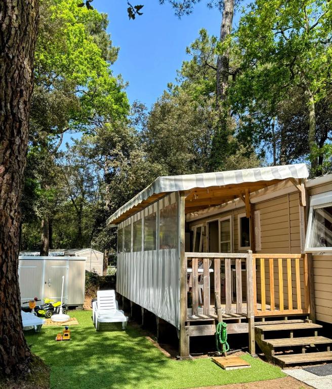 une petite maison dans une cour avec un arbre dans l'établissement Bungalow familial à Saint-Brevin-les-Pins avec piscine partagée_2, à Saint-Brévin-les-Pins