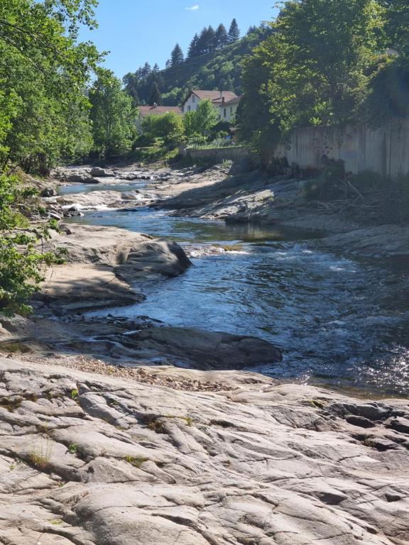 een rivier met rotsen en een huis op de achtergrond bij Chez Marilou in Arcens